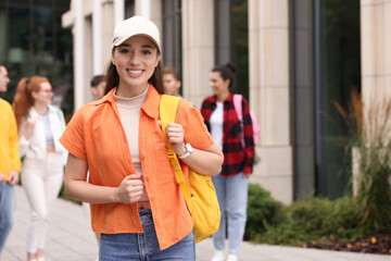 Students spending time together outdoors. Happy young woman with backpack, selective focus