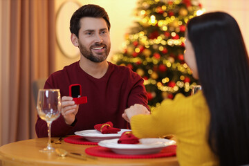 Man with engagement ring making proposal to his girlfriend at home on Christmas, selective focus