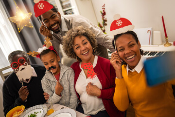 Family having good time with fun glasses, hats, mouth..Christmas time.