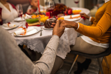 Family praying before eating delicious Christmas dinner.