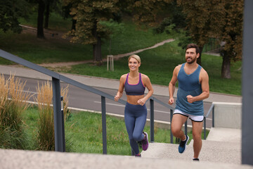 Healthy lifestyle. Happy couple running up stairs outdoors