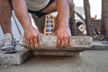 Installing new pavement or floor outside from large concrete tiles, closeup detail on male worker...