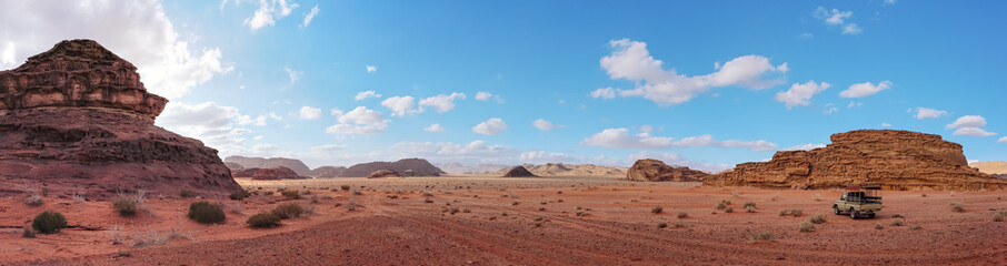 Red orange landscape in Jordan Wadi Rum desert, mountains background, small off road vehicle on side