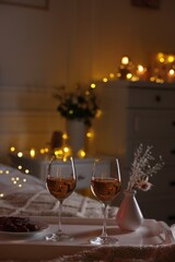 Glasses of wine in bedroom adorned for romantic evening. Space for text