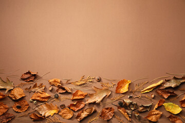 Flat lay composition with dry autumn leaves on brown background, space for text