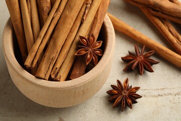 Bowl with cinnamon sticks and star anise on light table, closeup
