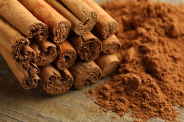 Cinnamon sticks and powder on wooden table, closeup