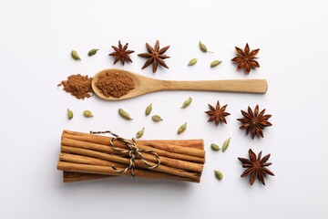 Cinnamon sticks, star anise and cardamom pods on white background, flat lay