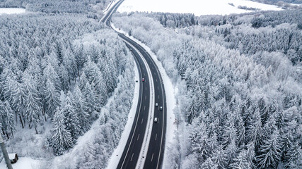 Landstraße durch verschneiten Wald im tiefsten Winter