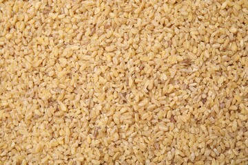 Uncooked organic bulgur as background, top view