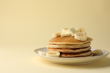 Delicious pancakes with bananas, honey and butter on beige background. Space for text