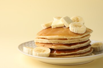 Delicious pancakes with bananas, honey and butter on beige background, closeup. Space for text