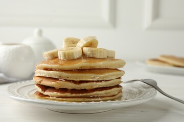 Delicious pancakes with bananas and honey on white wooden table, closeup