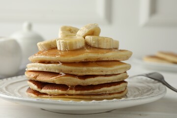 Delicious pancakes with bananas and honey on white wooden table, closeup
