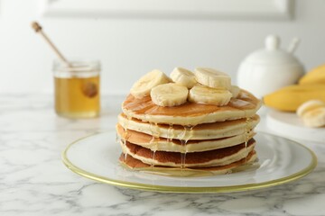 Delicious pancakes with bananas and honey on white marble table, closeup. Space for text