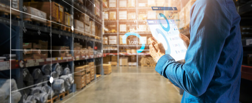 A businessman checks the state of the warehouse and the number of merchandise there while leaning back and using a tablet.