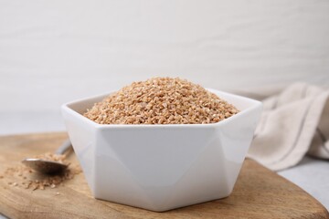 Dry wheat groats in bowl on light table, closeup