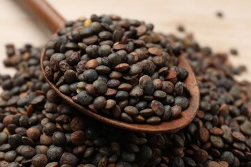 Spoon and many raw lentils on table, closeup