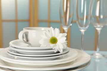 Set of clean dishware and flower on light blue table, closeup