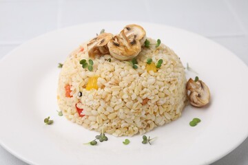 Delicious bulgur with vegetables, mushrooms and microgreens on table, closeup