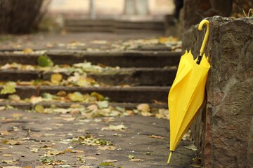 One yellow umbrella near stairs outdoors. Space for text