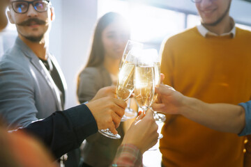 Business people celebrate with glasses of champagne in the office at a corporate event. A group of...