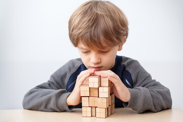 Young Caucasian blond boy with wooden puzzle, autism spectrum disorder concept