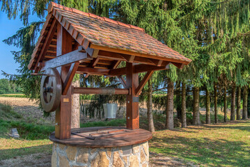 Rustic stone well with bucket and drinking water.