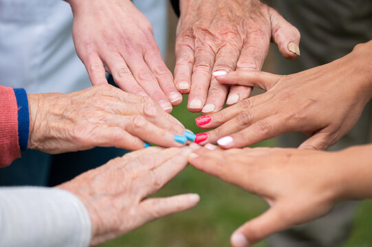 Concept of family, aging society or teamwork, hands showing unity with putting hands together, senior wrinkled hands of old people together with other young people hands. High quality photo