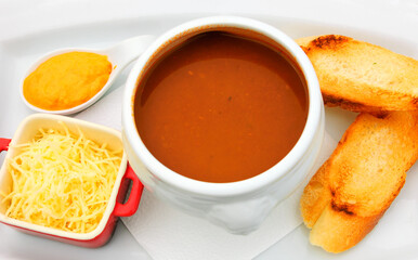 French fish soup Bouillabaisse served with pepper mayonnaise, toasted baguette and grated cheese. 