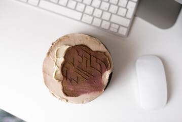 Coffee chocolate bento cake on desktop with keyboard and mouse