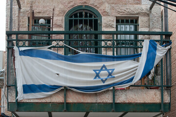 Tattered flag of Israeli draped across a Jerusalem balcony