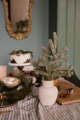 Branches of spruce or fir in a ceramic vase on a festive table decorated for Christmas