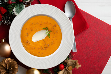 Carrot and pumpkin cream with cream and nuts. Christmas food served on a table decorated with Christmas motifs.