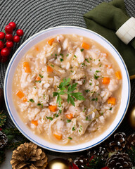 Soupy rice with artichokes and carrots. Typical Spanish gastronomy dish.  Christmas food served on a table decorated with Christmas motifs.