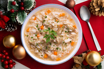 Soupy rice with artichokes and carrots. Typical Spanish gastronomy dish.  Christmas food served on a table decorated with Christmas motifs.