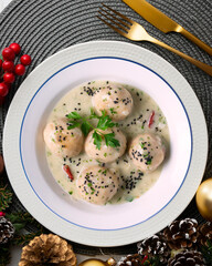 Fish meatballs with white wine sauce. Traditional tapas from Barcelona, ​​Spain. Christmas food on a table with decorations.
