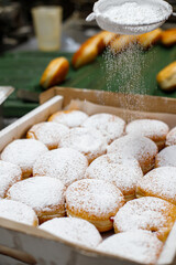 A baker sprinkles sugar powder on Hanukkah donuts in a bakery.