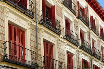 Tuinposter Vintage windows with red colourful shutters on rich classical facade downtown Madrid, Spain © Yana Demenko