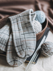 Hand knitted socks with needles and yarn ball in a basket. Concept for handmade and hygge slow life.