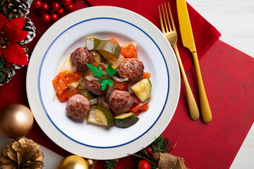 Meat meatballs with tomato sauce and vegetables. Christmas food on a table with decorations.