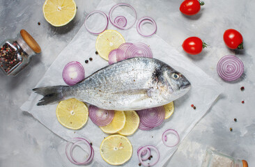 Raw dorado fish on cutting board on concrete table with ingredients for cooking. Top view.