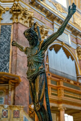 statue of crucified jesus christ with the background of organ pipes inside the basilica SS Ambrogio...