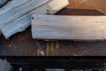 Сhopped firewood. Rusty metal grill background. Sunlight.