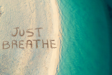 High angle of view of handwritten Just breathe on sandy beach at suny day,relax and summer concept, Zanzibar , Tanzania. - obrazy, fototapety, plakaty