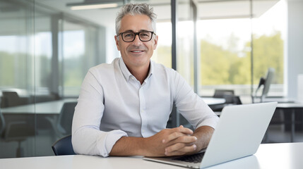 Middle aged man working on a laptop in his modern office