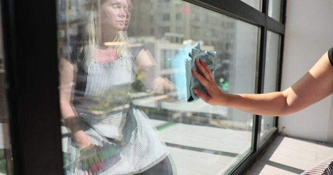 Closeup of woman hand with blue rag wiping window and plastic frame from dust in office