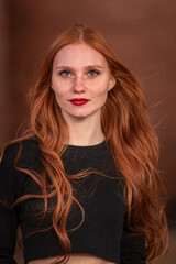 Portrait of a young beautiful red-haired girl in dark clothes in a low key.