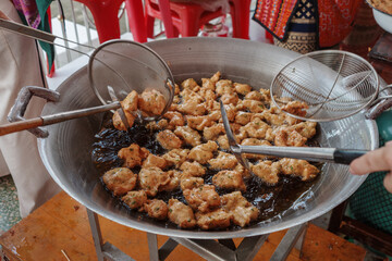 Deep fried Thai fish cake in the oil and wok pan at the outdoor market stall in Thailand. 