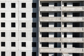 Facade of a panel multistory building under construction. Gray geometric background.